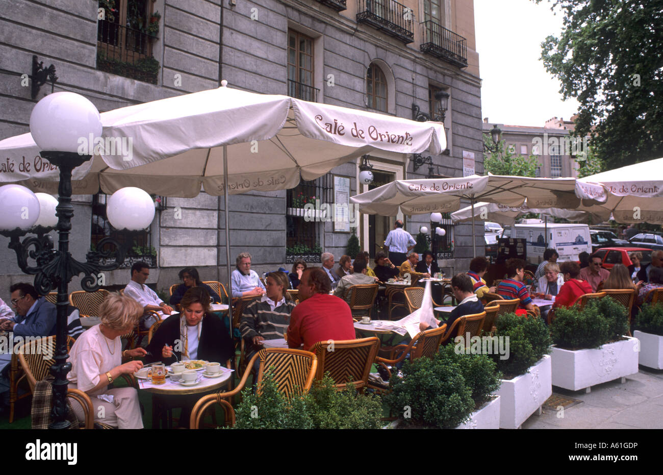 Life in Spain the Cafe de Oriente with tourists and umbrellas in Madrid Spain Stock Photo