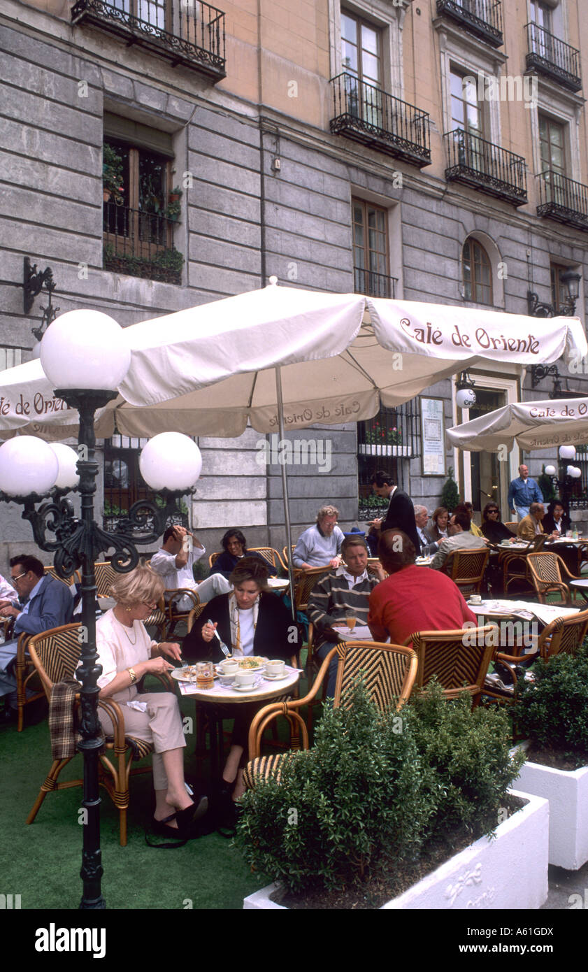 Life in Spain the Cafe de Oriente with tourists and umbrellas in Madrid Spain Stock Photo