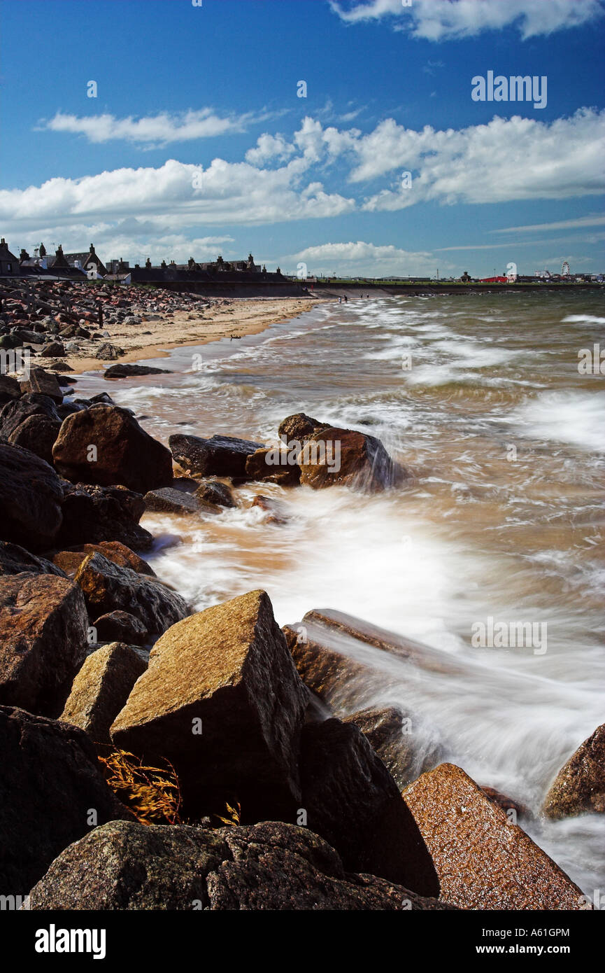 Portrait format image of Aberdeen Beach and promenade Scotland against a blue sky and rocky foreground Stock Photo