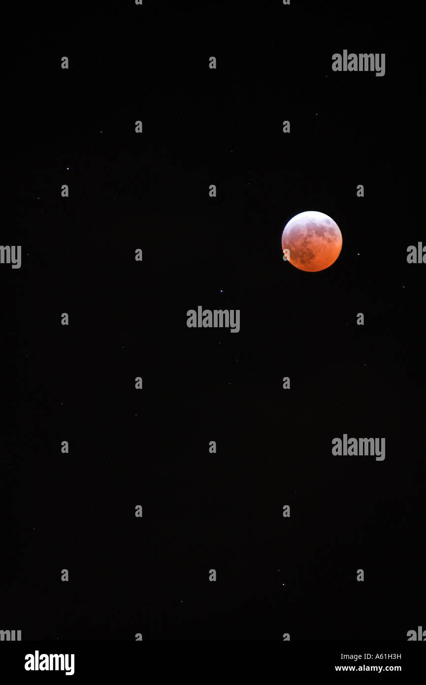 The moon during an eclipse with red glow surrounded by pitch blak sky Stock Photo