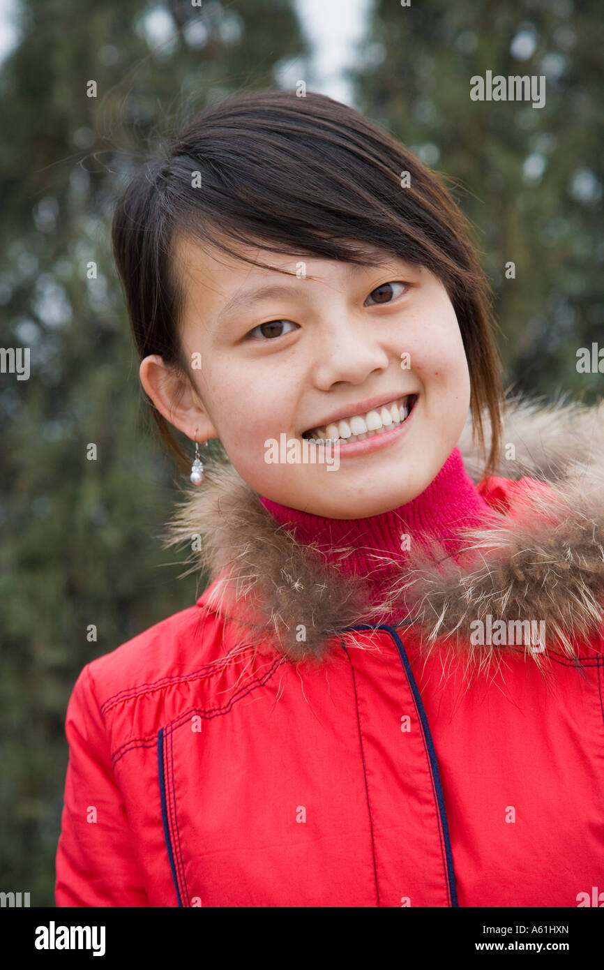 Beautiful smiling modern Chinese girl head inclined to left in red coat with fur trimmings Xi'an China JMH2560 Stock Photo