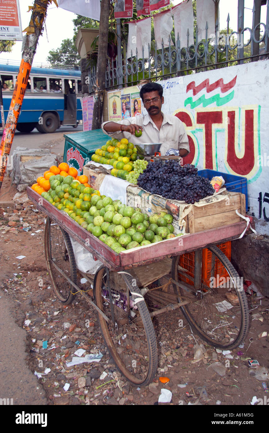 Man selling fresh fruit from a mobile cart on a street corner in
