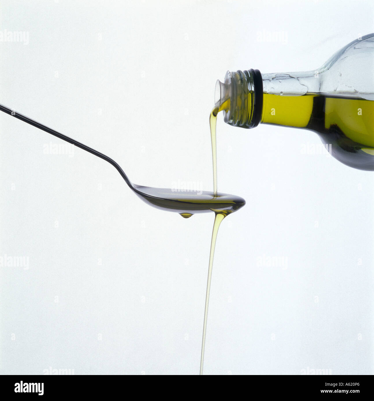 Olive oil pouring on to spoon Stock Photo