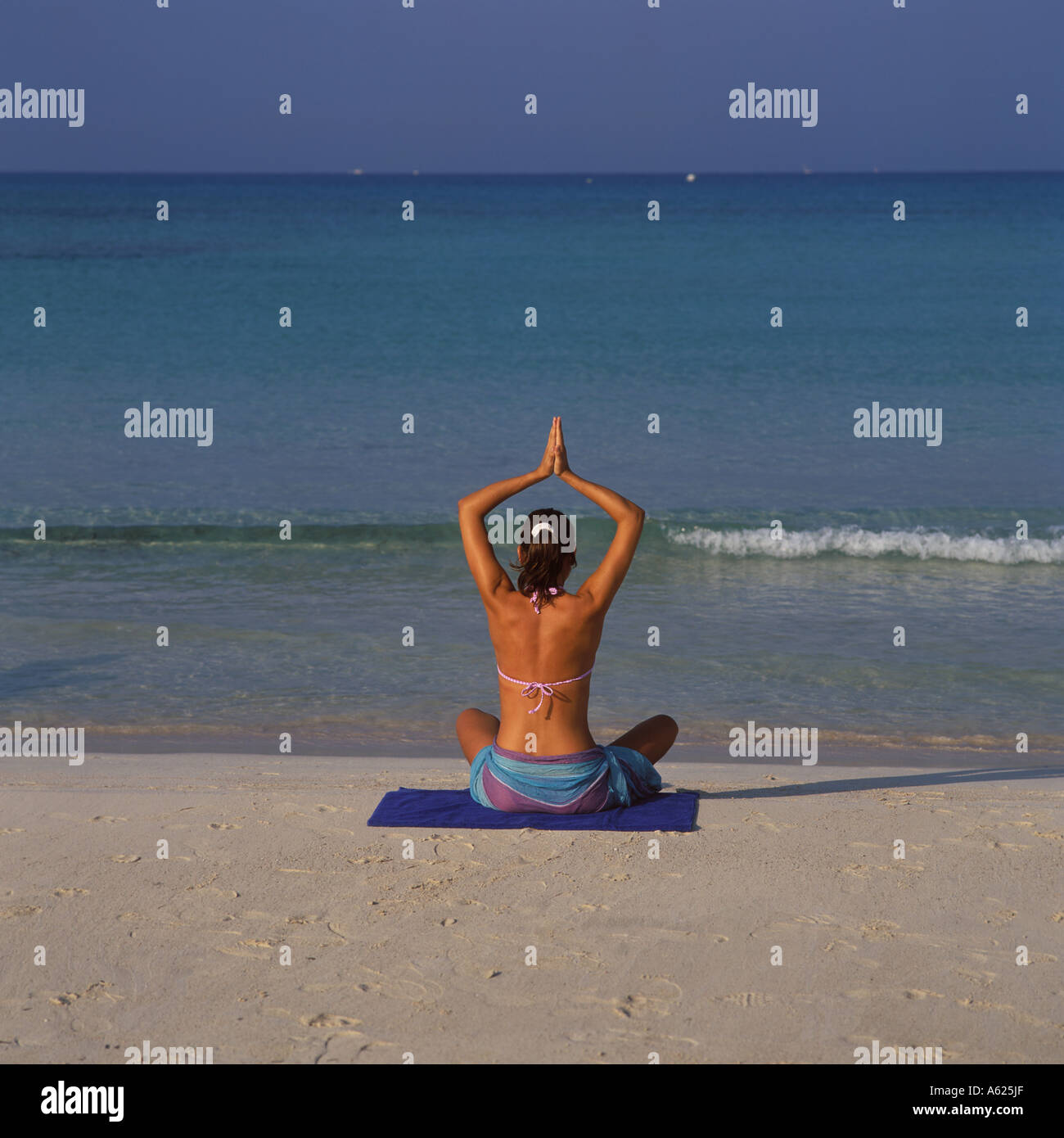 Scene on Es Trenc beach Platja de Trenc in SE Mallorca well tanned girl doing meditation yoga exercises by waters edge Baleares Stock Photo