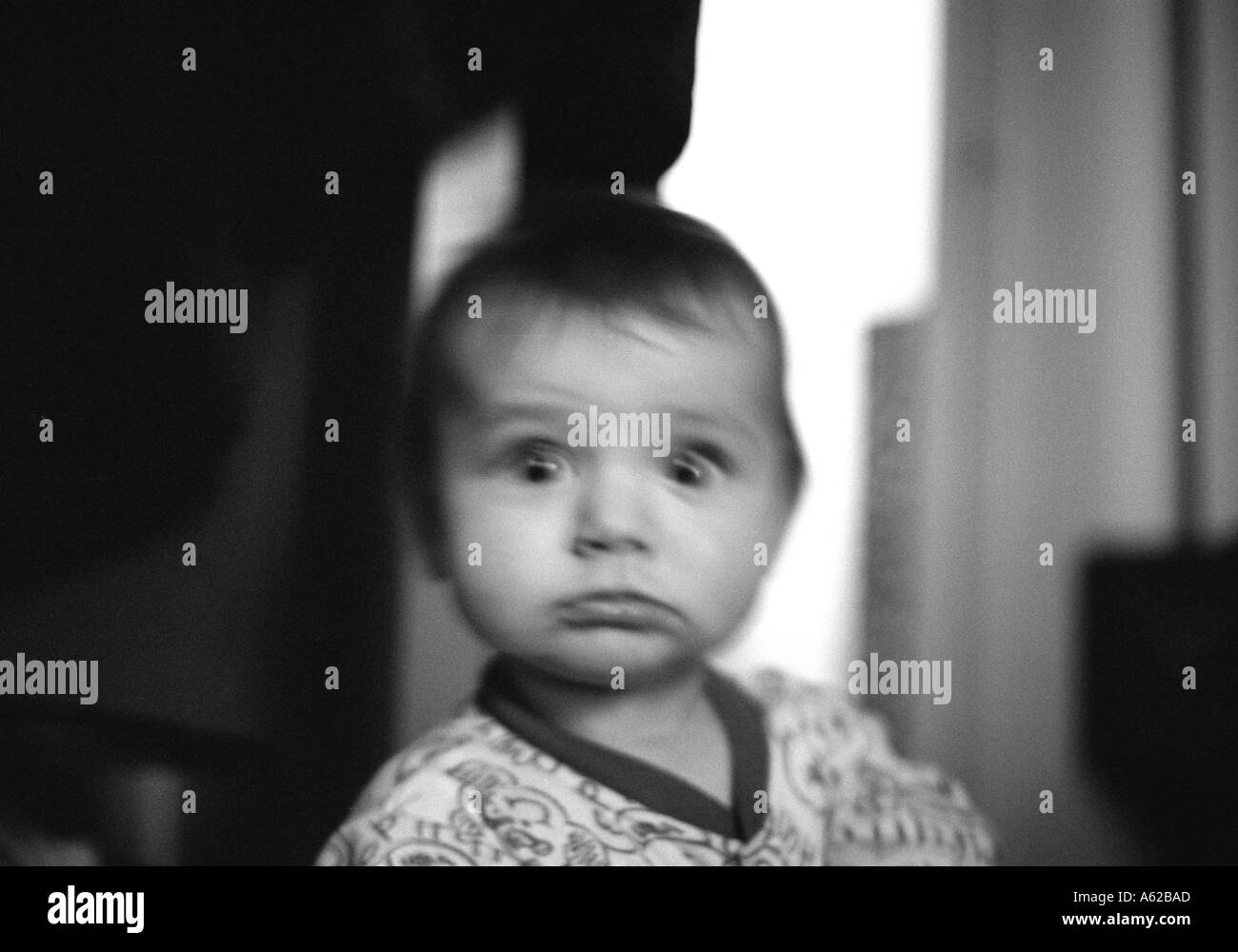 blurred head and shoulders shot of a baby pulling funny shocked expression Stock Photo
