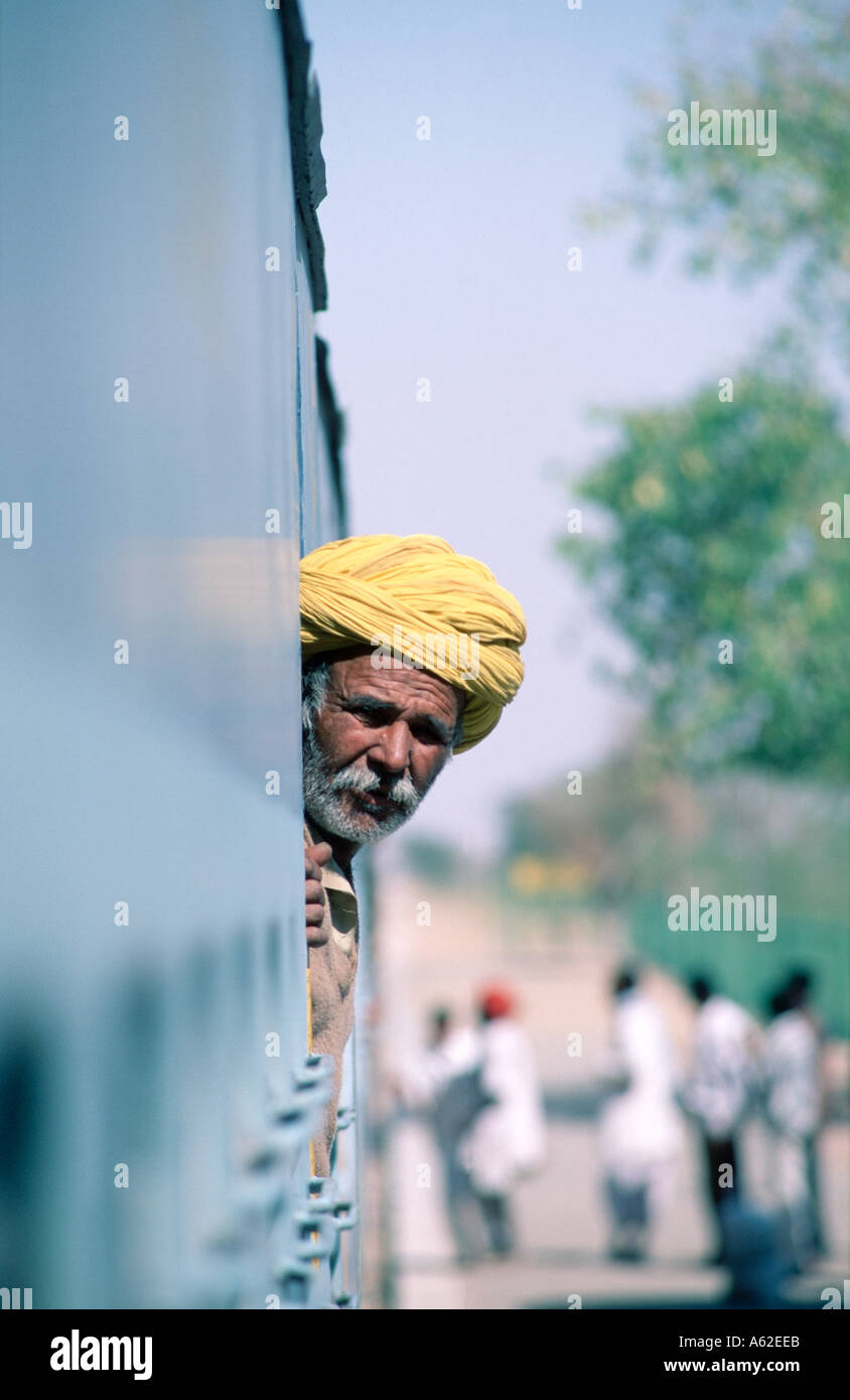 Am an wearing a bright yellow turban leans out of train Stock Photo