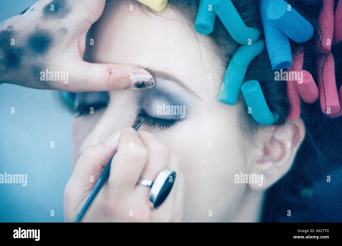 Close-up of person's hand applying eye shadow on young woman's eye Stock Photo