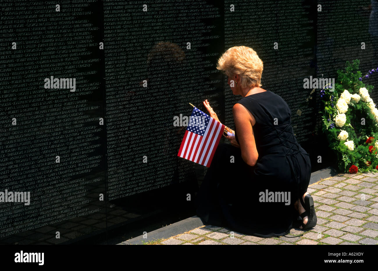 Horizontal shot of widow mourning at the Vietnam Memorial Wall in Washington DC near her loved one Stock Photo
