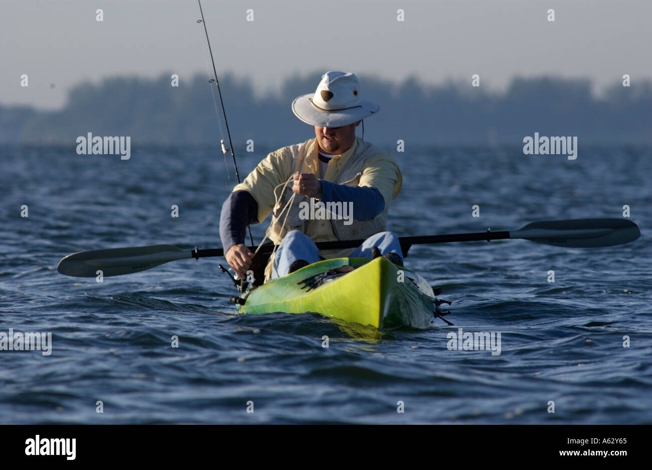 Man fishing from kayak pulling up anchor Intracoastal waterway Indian