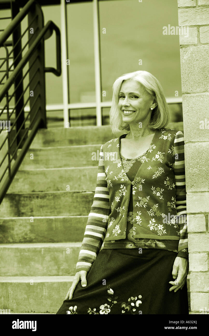 Mature woman standing on a staircase and smiling Stock Photo - Alamy