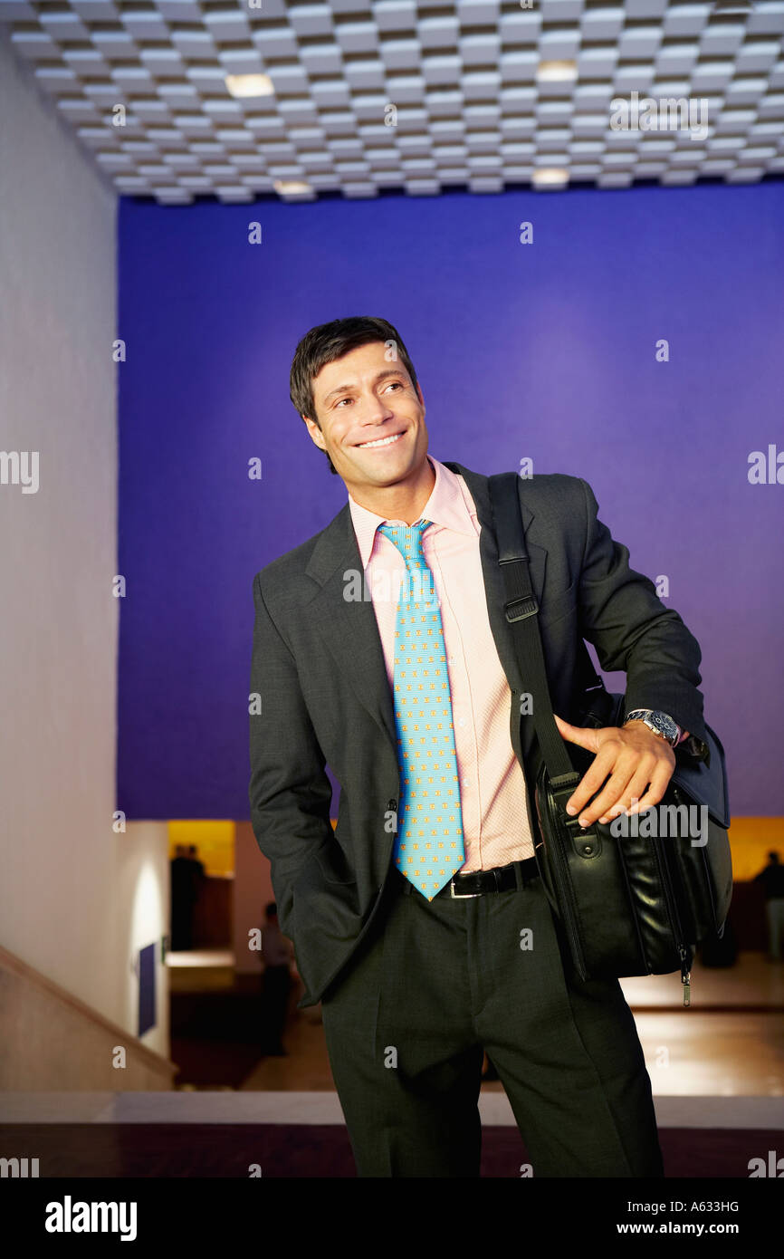 Businessman carrying a bag and smiling Stock Photo - Alamy