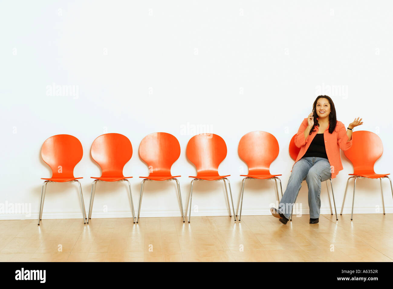 Mid adult woman sitting on a chair and smiling Stock Photo - Alamy