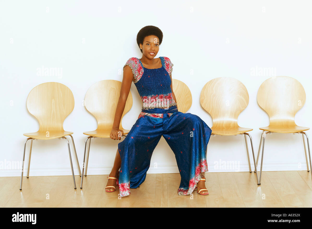 Portrait of a young woman sitting on a chair and smiling Stock Photo ...