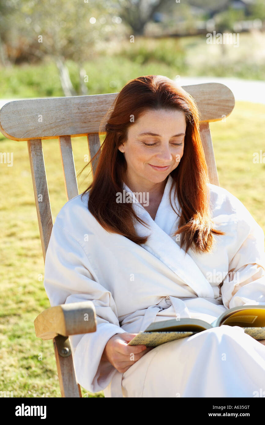 Mature woman sitting in an armchair and reading a book Stock Photo - Alamy