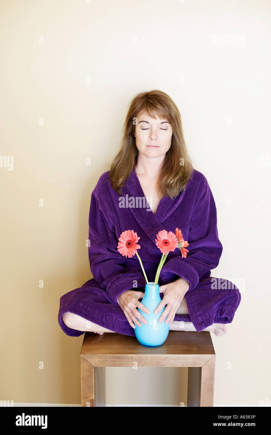 Mid adult woman sitting on a stool with her eyes closed and holding a