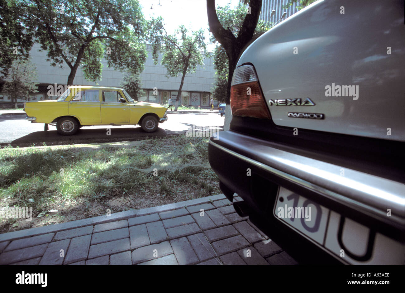 A shiny new Korean Daewoo car near an old Soviet-era Moskvitch in Tashkent, Uzbekistan Stock Photo