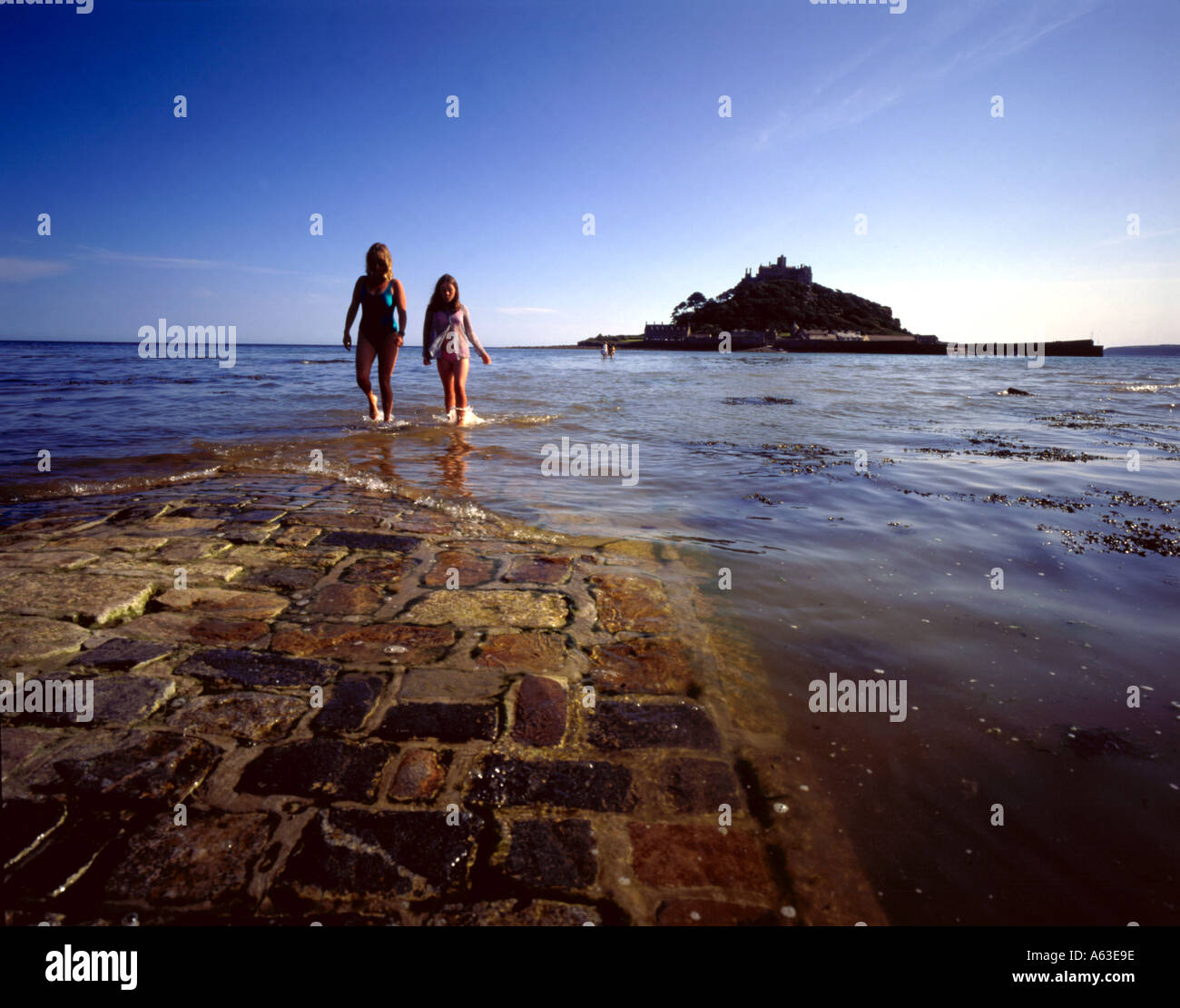 Tourists walk from St Michaels Mount in Cornwall UK Stock Photo
