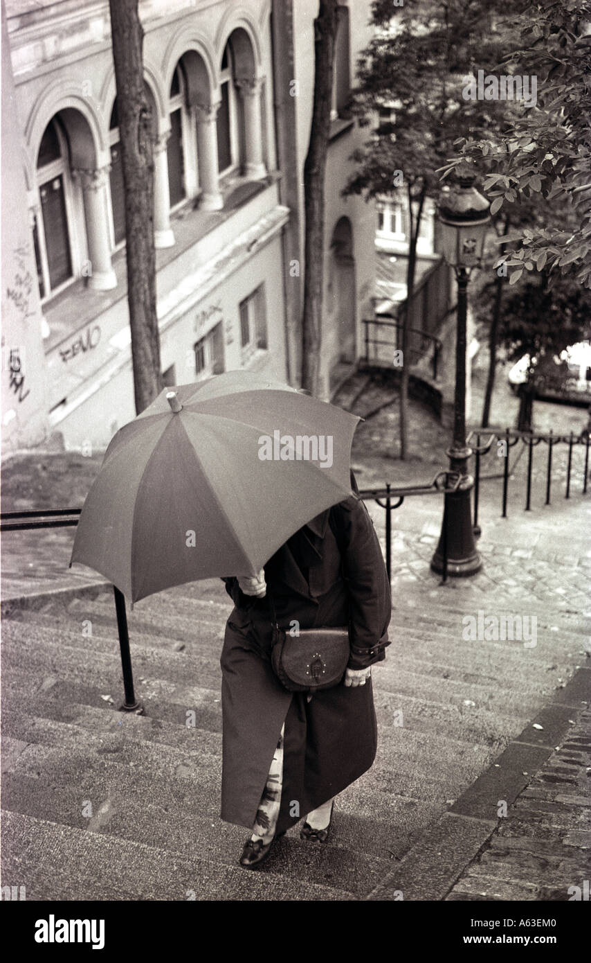 Woman with umbrella walking upstairs Stock Photo