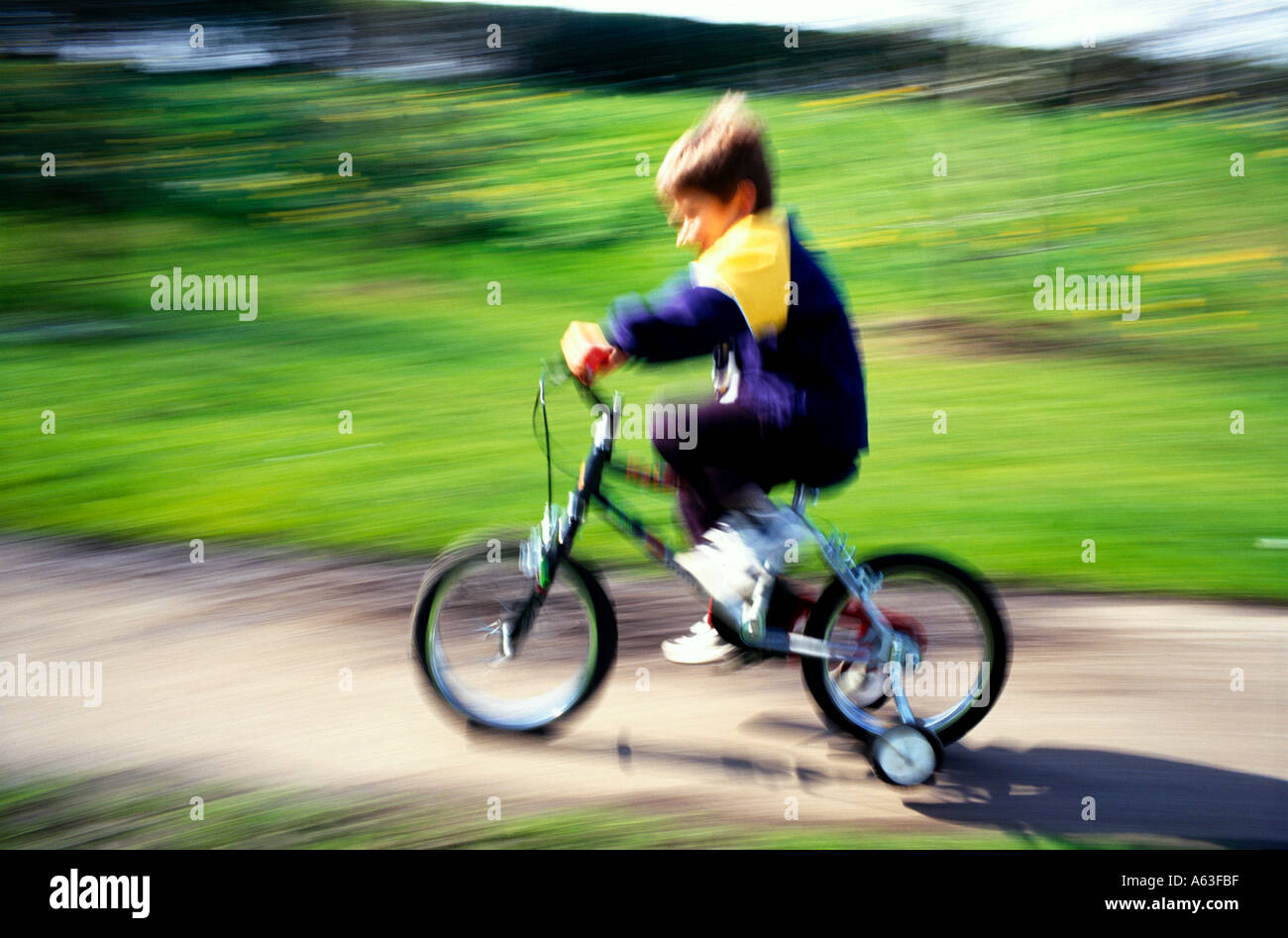 Young boy on a bicycle with stabilisers Stock Photo