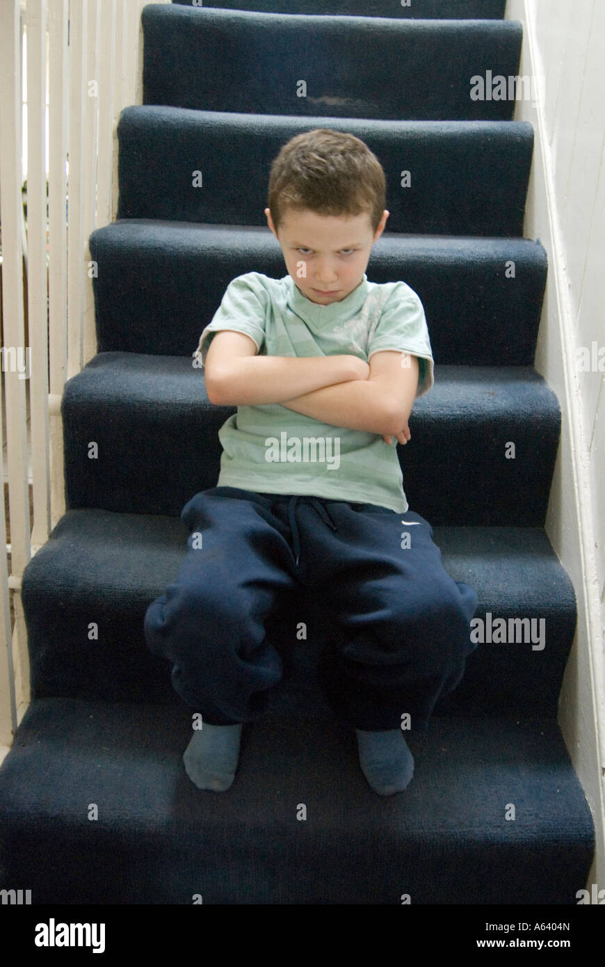 Young boy who has been told off sulking on the stairs England UK Stock ... image picture