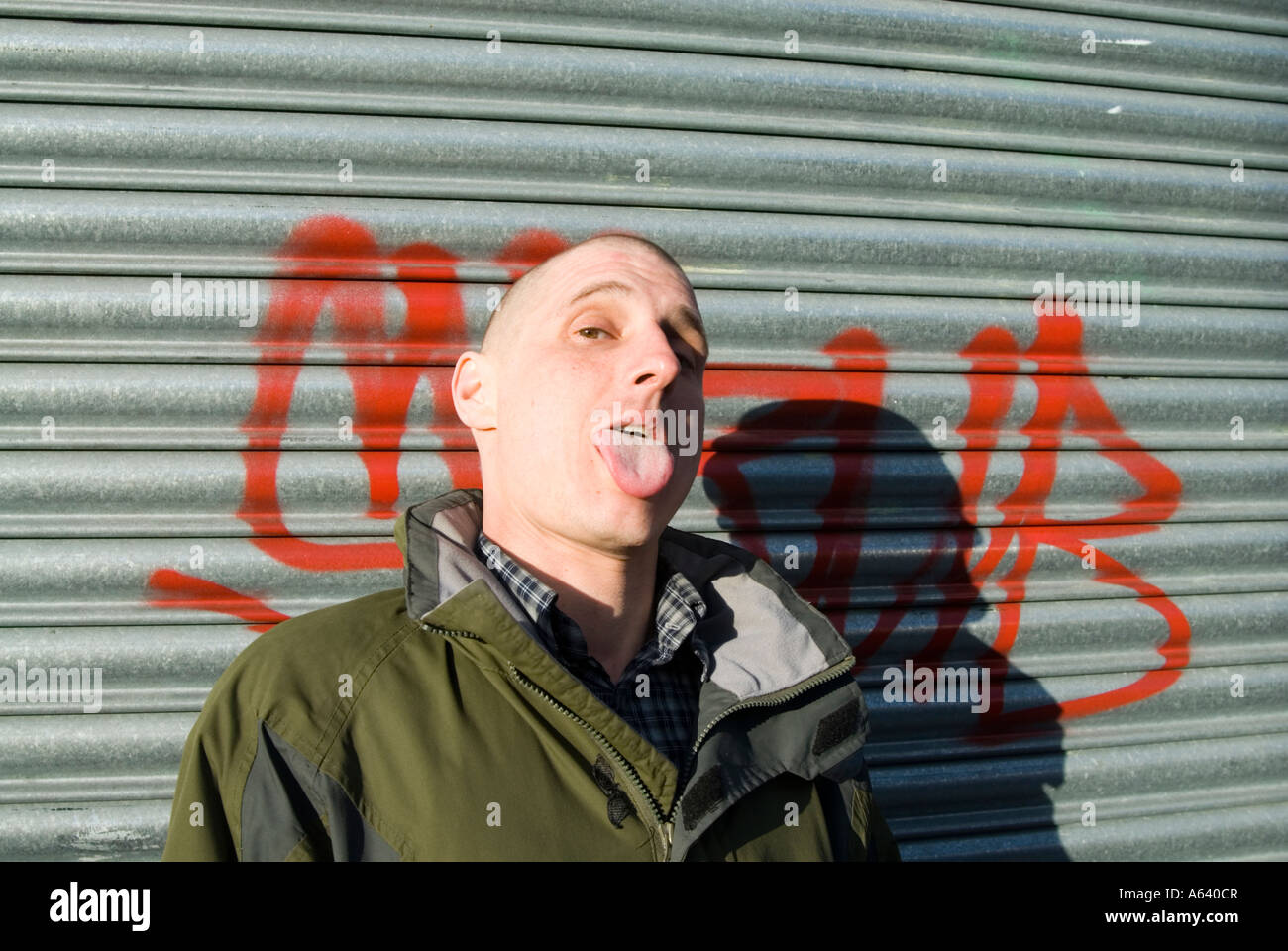 Skinhead man sticking his tongue out London England UK Stock Photo