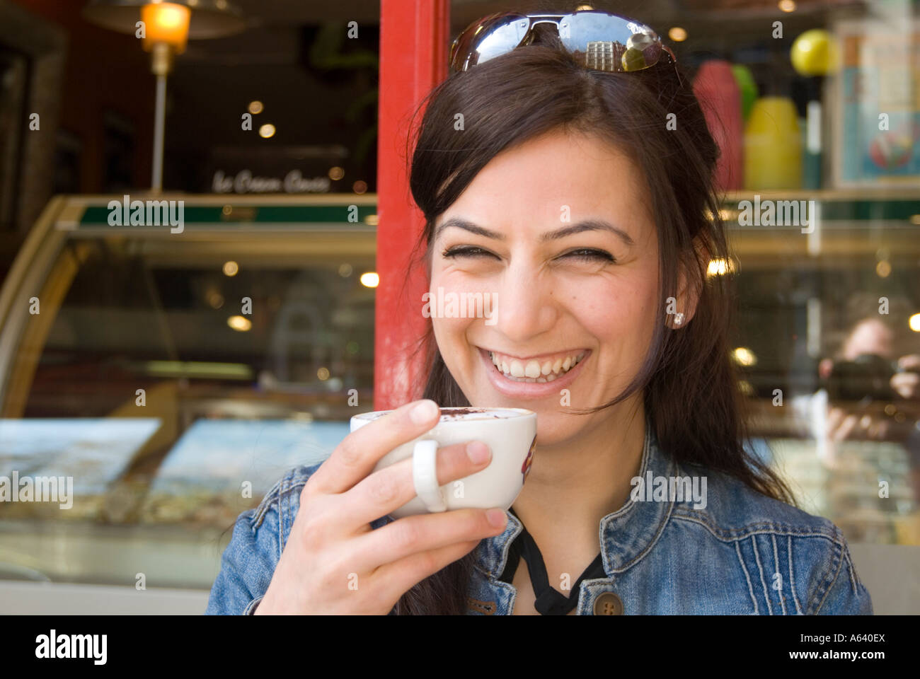 Beautiful young Turkish woman drinking cup of cappuccino coffee at a cafe, London England UK Stock Photo