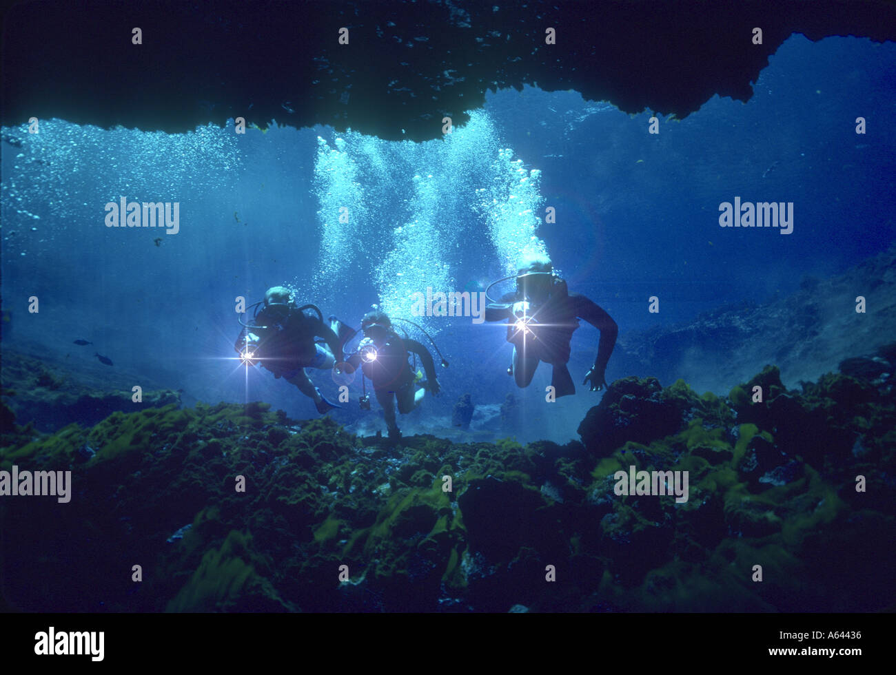 three skin divers exploring underwater cave Stock Photo