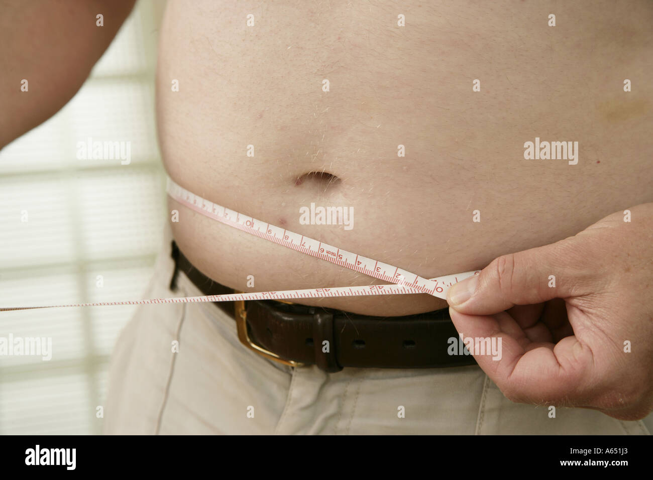 Man using tape measure to measure his stomach. Stock Photo