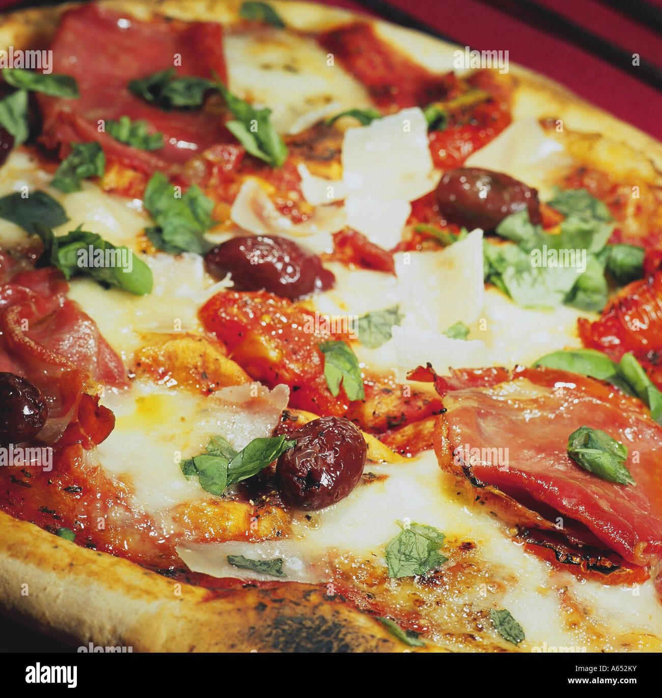 A home-made, stone-baked pizza topped with Parma ham, buffalo mozzarella, olives, baby plum tomatoes, shaved parmesan and basil. Stock Photo