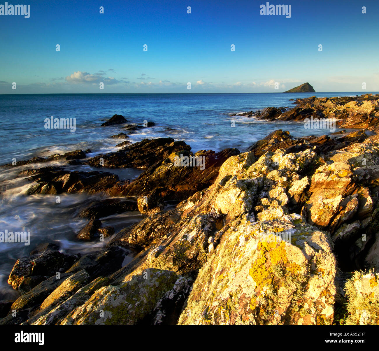 Beautiful dawn light at Wembury Beach with the sea swirling around the exposed rocks and the Mew Stone on the horizon Stock Photo