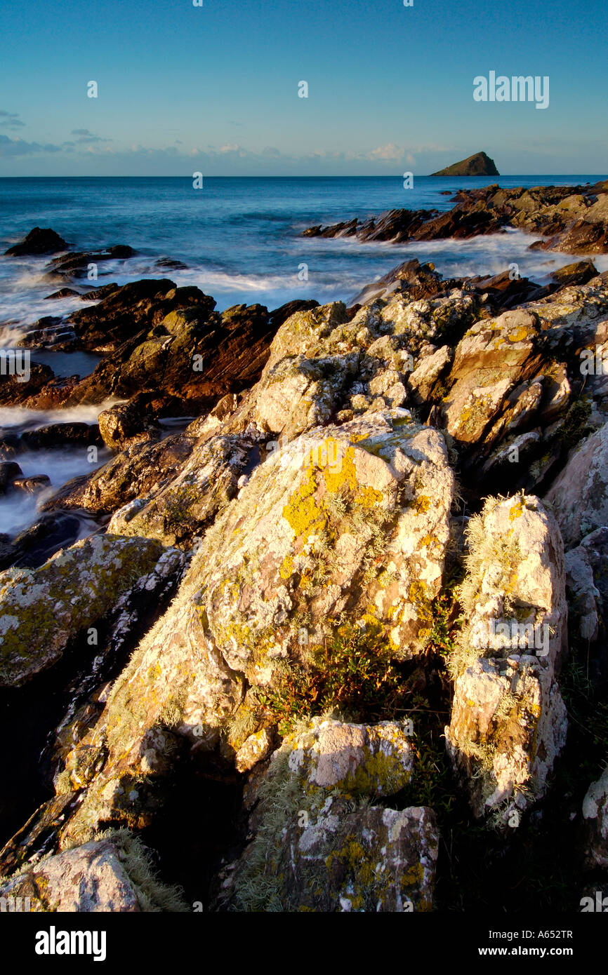 Beautiful dawn light at Wembury Beach with the sea swirling around the exposed rocks and the Mew Stone on the horizon Stock Photo