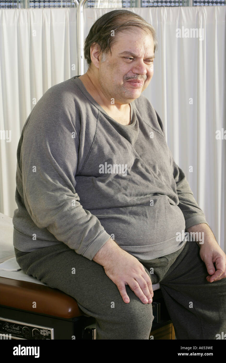 An overweight patient waits in the exam room for a healthcare worker. Stock Photo
