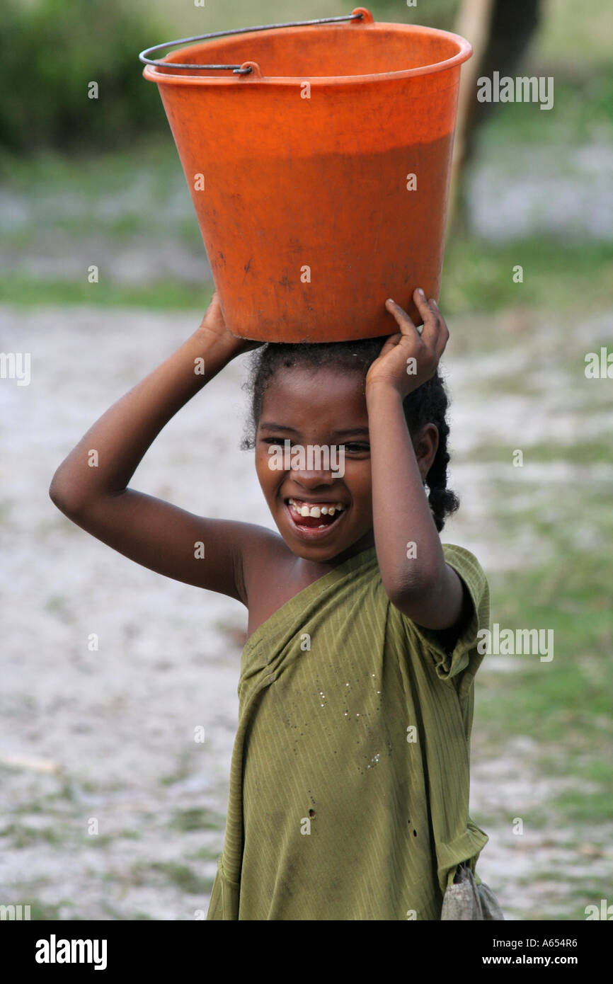 Manakara, Madagascar, young girl balancing a bucket of water on her