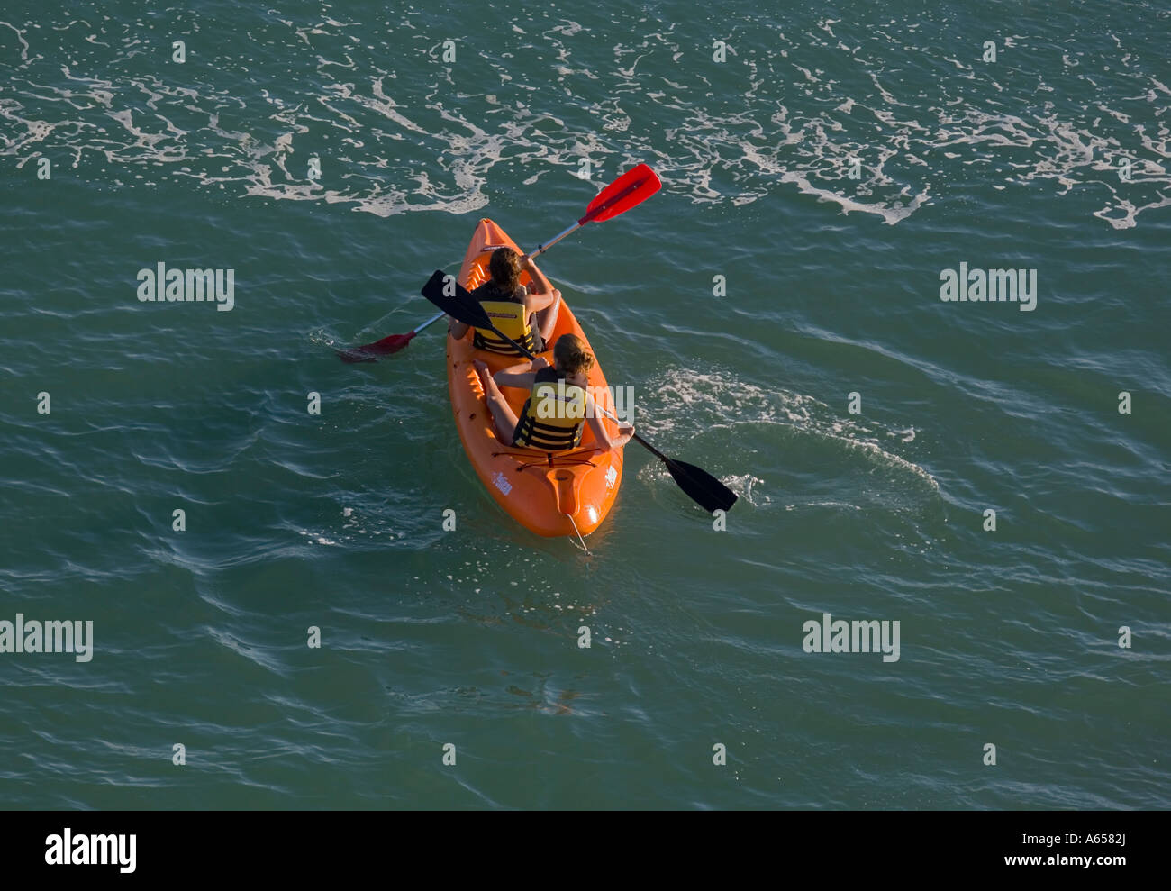 Two girls paddling a kayak Stock Photo - Alamy