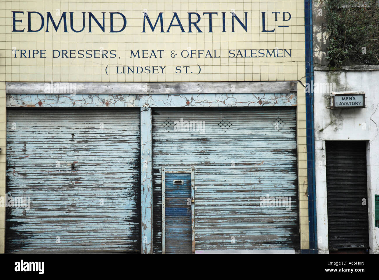 Front of dilapidated shop selling tripe and offal next to men's public toilet Smithfield Meat Market London Stock Photo