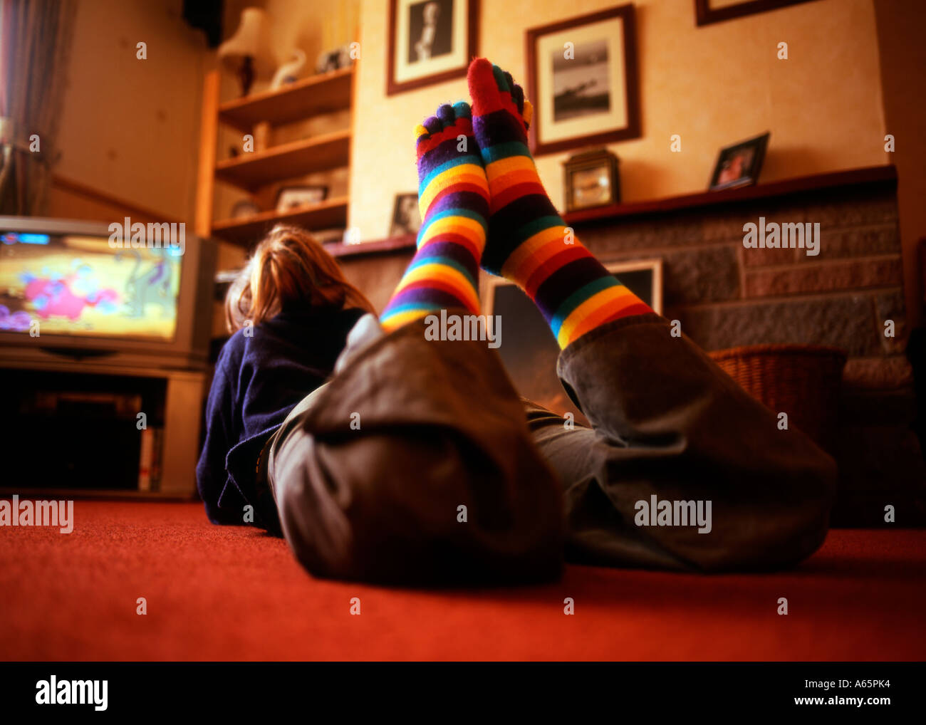 https://c8.alamy.com/comp/A65PK4/young-girl-watching-the-tv-in-rainbow-coloured-toe-socks-A65PK4.jpg