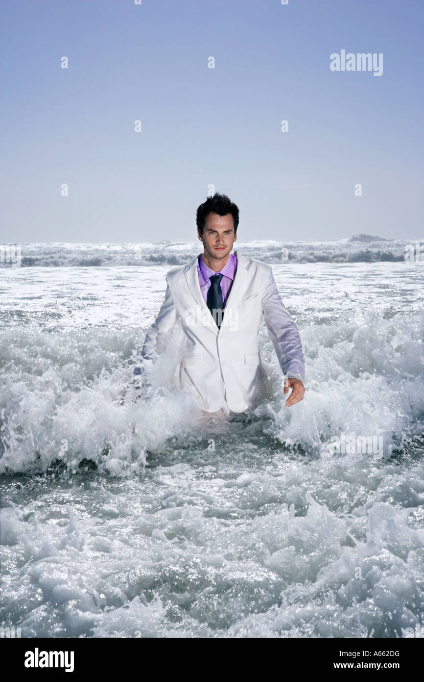 Man walking in sea, being washed by waves, portrait Stock Photo