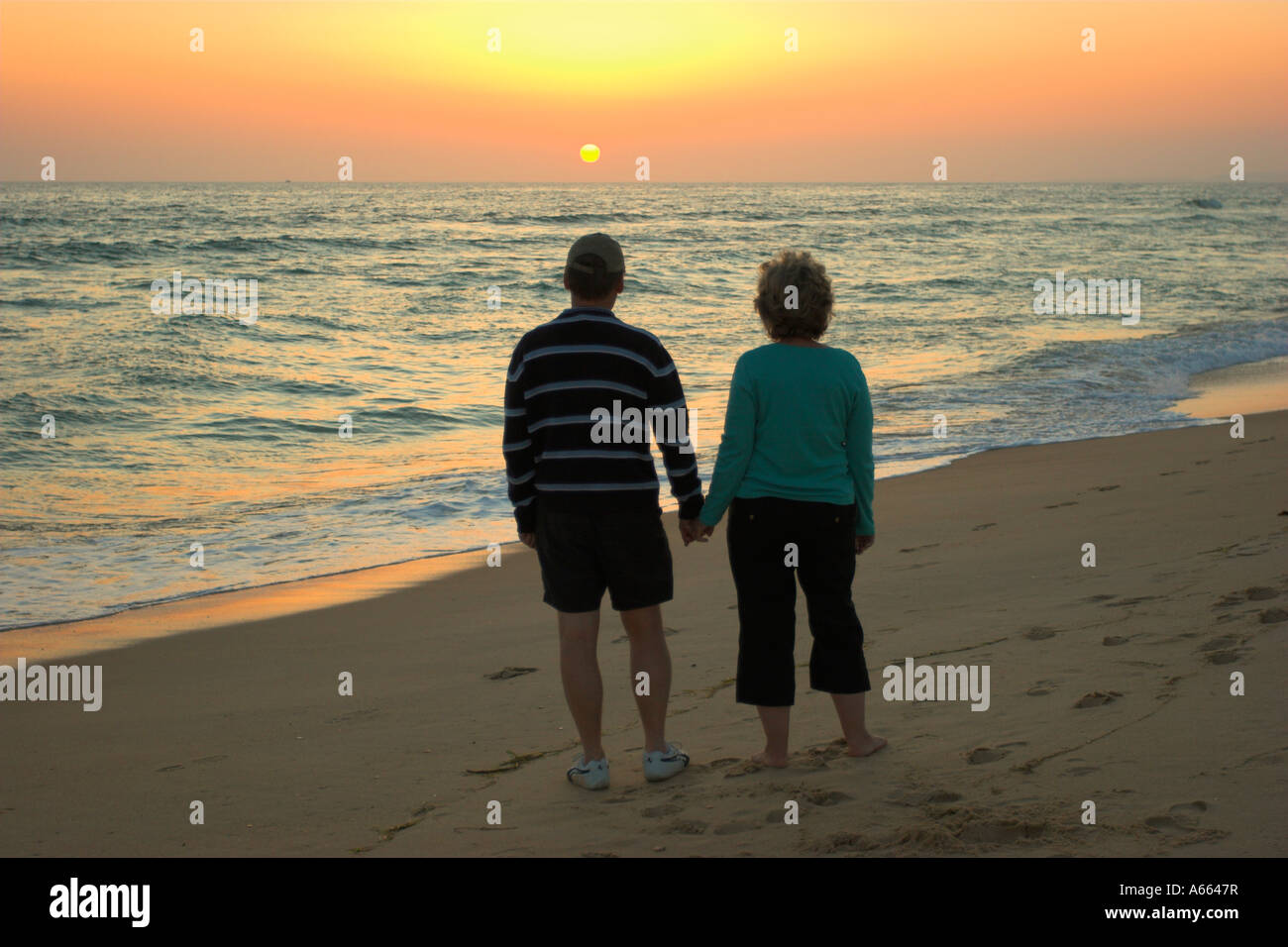 Couple holding hands watching the setting sun Stock Photo - Alamy