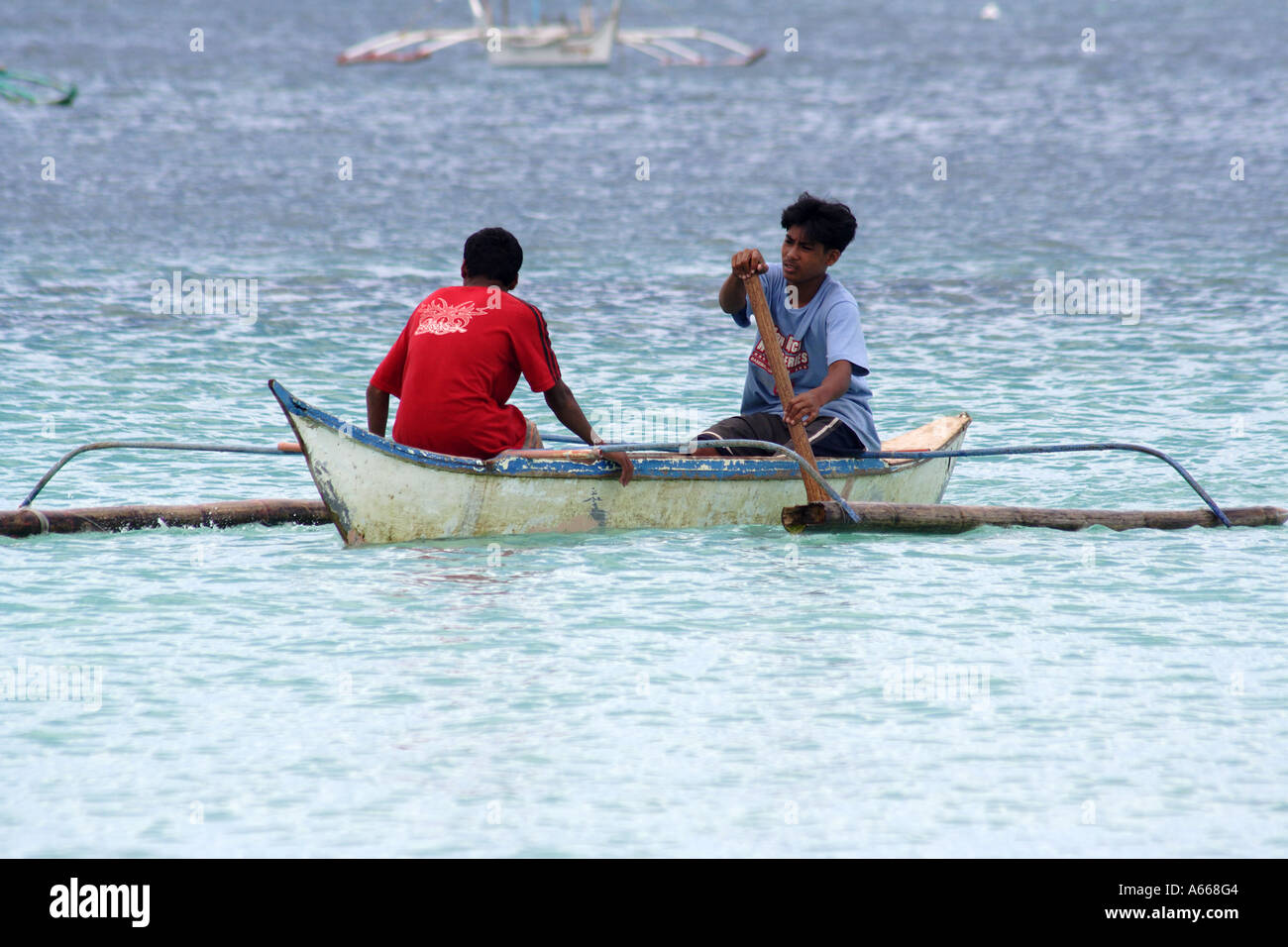 Boracay, Philippine Islands, two young men rowing an outrigger canoe Stock Photo