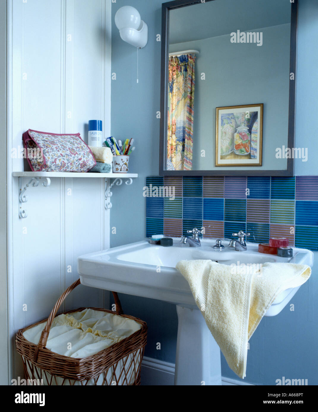 White Pedestal Basin Below Large Mirror In Pastel Blue Bathroom With Laundry Basket Stock Photo Alamy