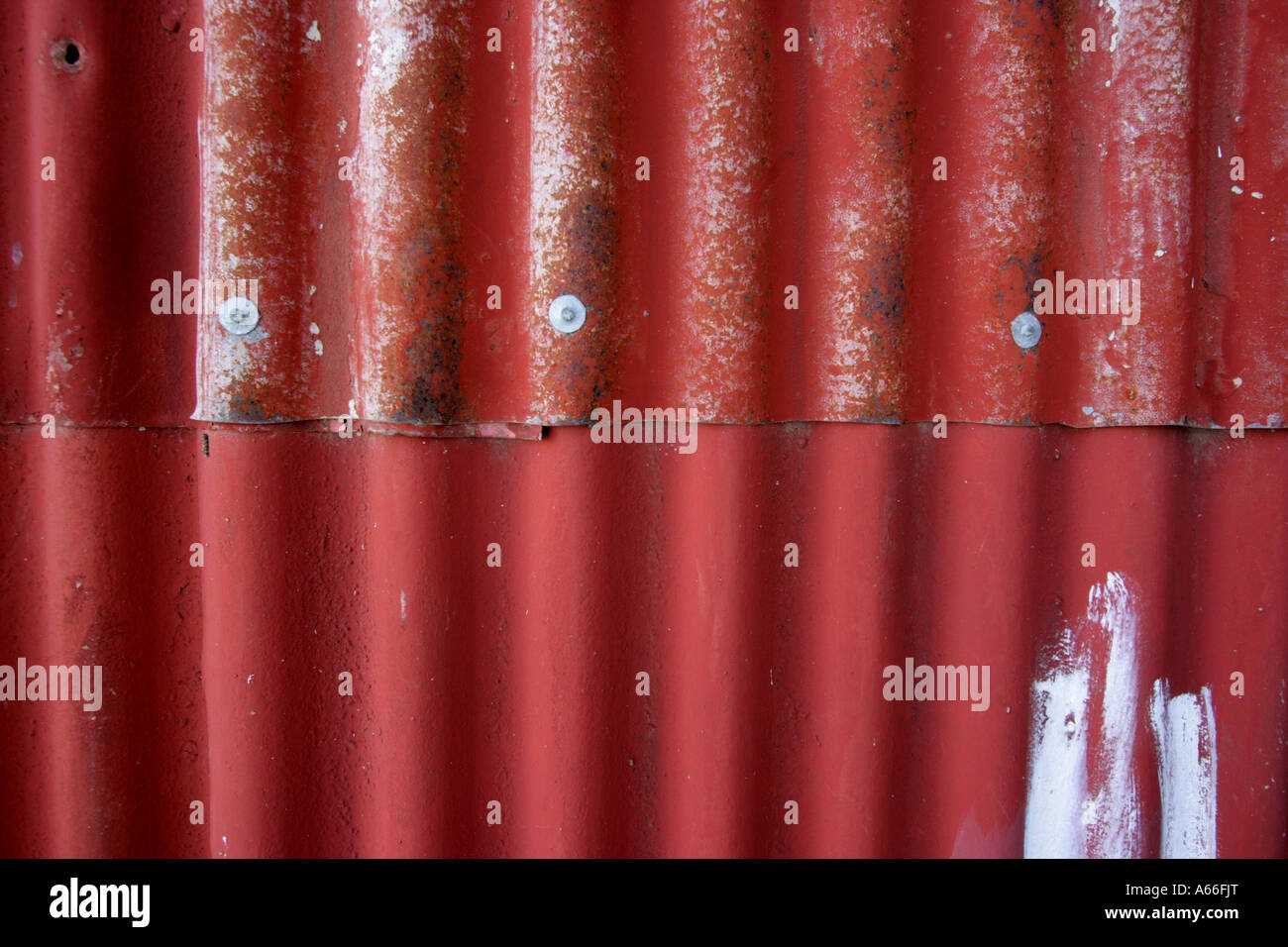 SHEETS OF RED AND SILVER CORRUGATED IRON ON A HOUSE /SHED WALL