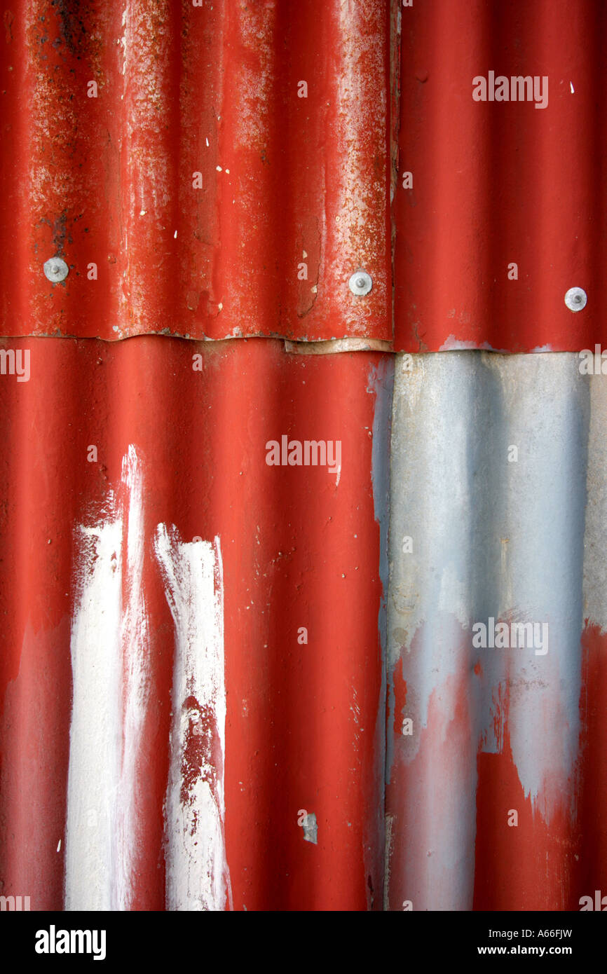 SHEETS OF RED AND SILVER CORRUGATED IRON ON A HOUSE /SHED WALL VERTICAL