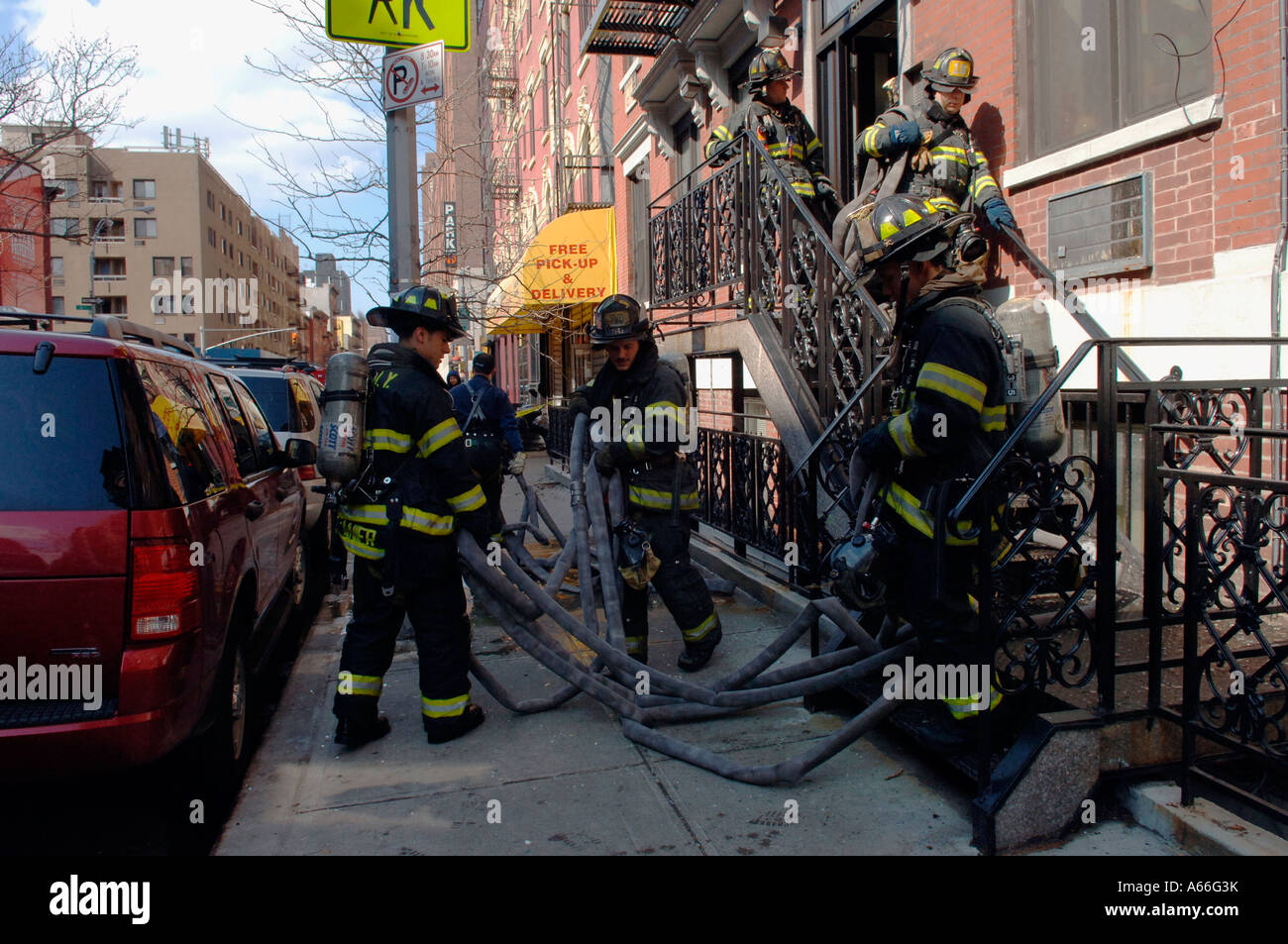 FDNY firefighters collect their hoses after fighting a fire in the ...
