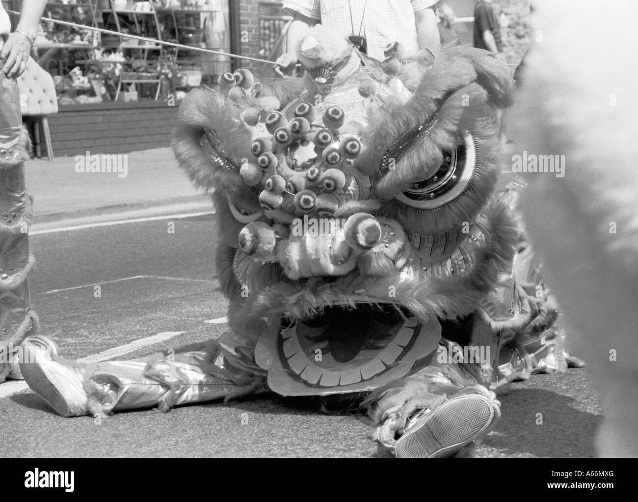 Black White Grainy Image of Exhausted Chinese Dragon Dancer Sitting in Cowley Road Carnival Procession Oxford England UK 2004 Stock Photo