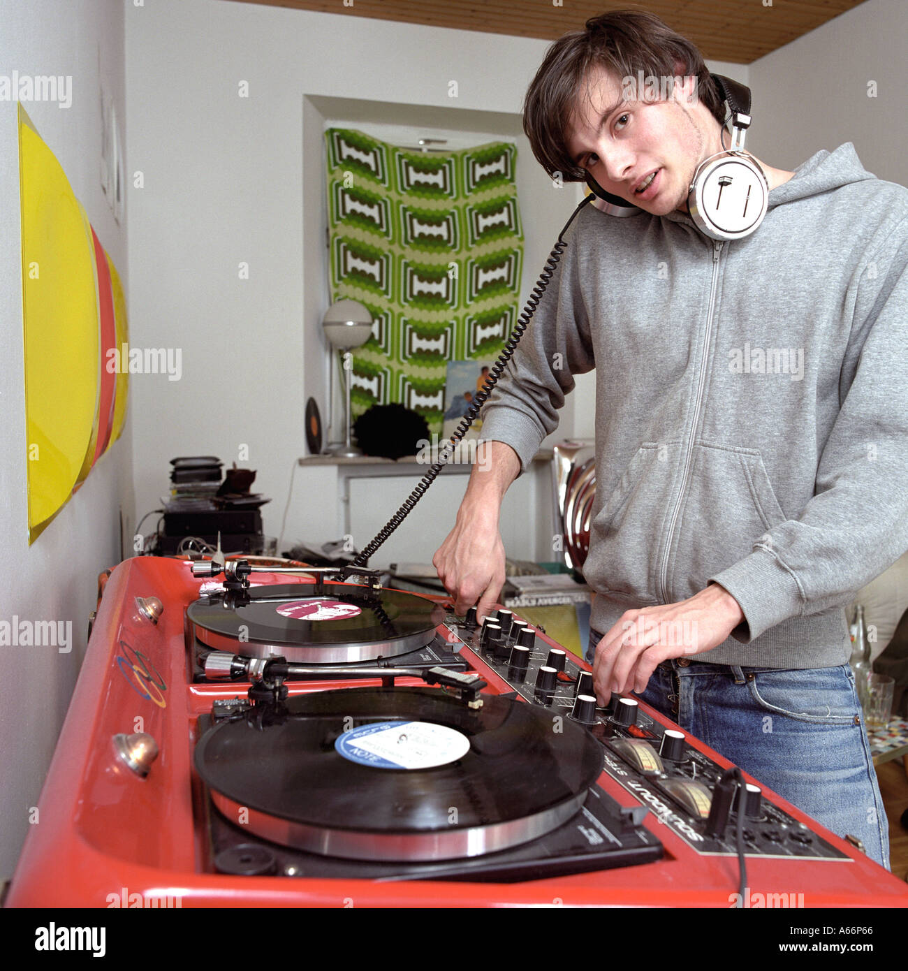 young DJ with headphones listening to records at a mixing desk Stock