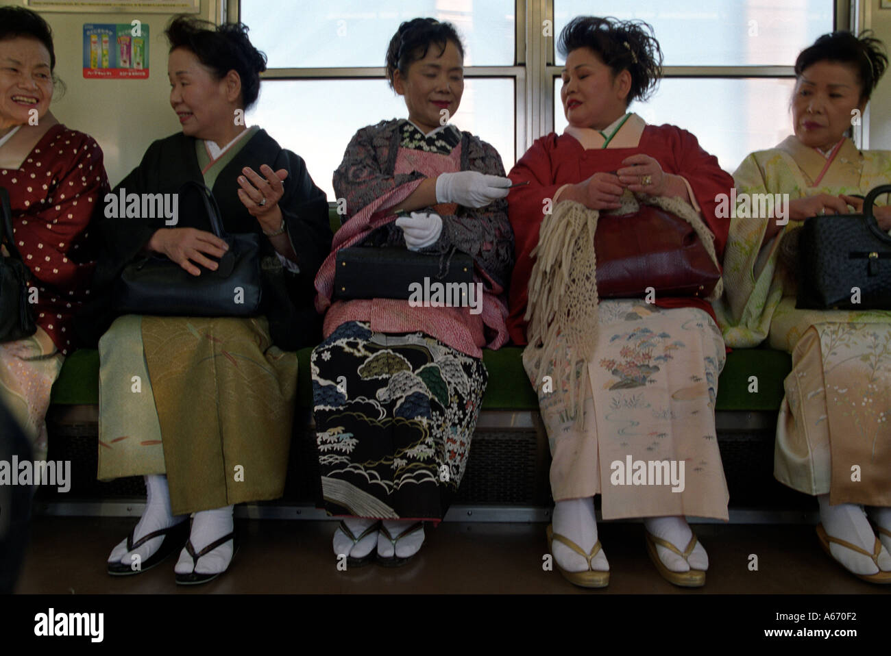 A group of Japanese ladies in kimono enjoy a joke on a train in Japan Stock Photo