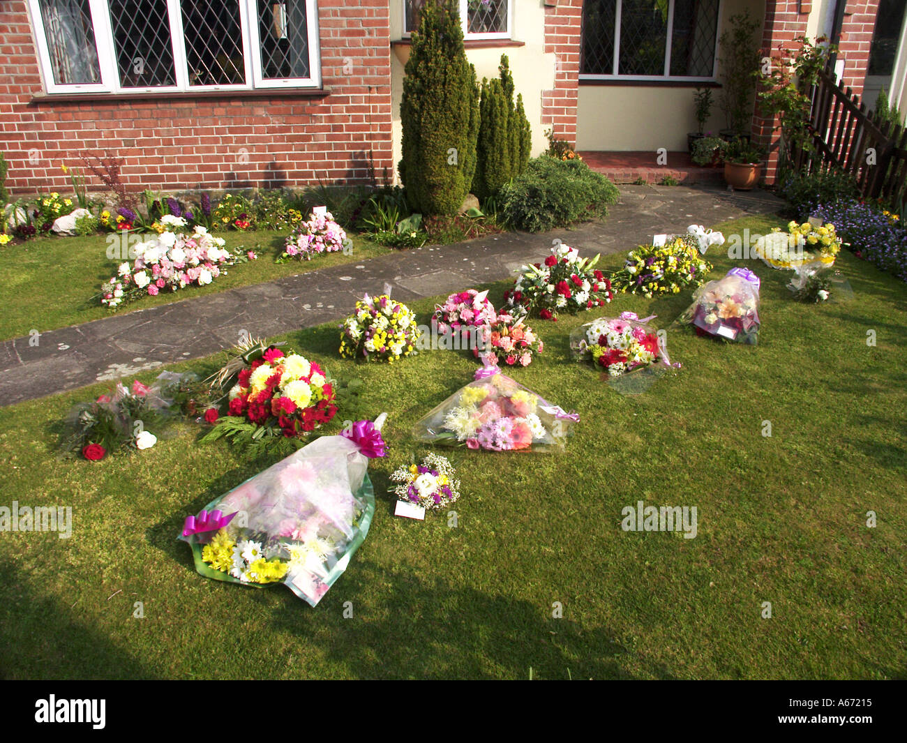 Floral remembrance tributes domestic front garden on grass lawn awaiting arrival of undertaker at home of deceased family member Essex England UK Stock Photo