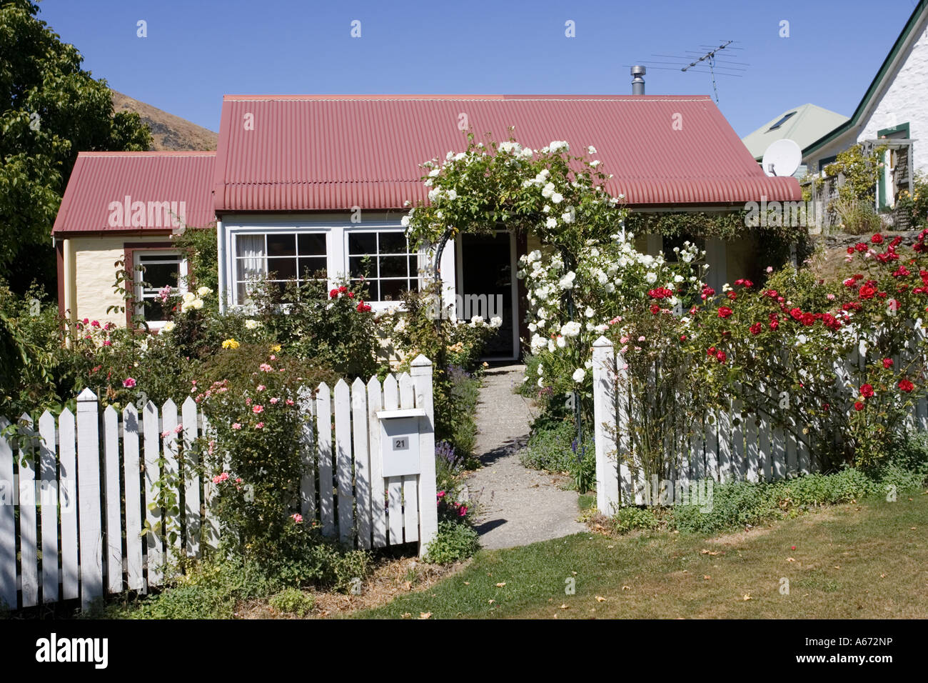 Small cottage with rose garden former in goldrush town of Arrowtown near Queenstown New Zealand Stock Photo