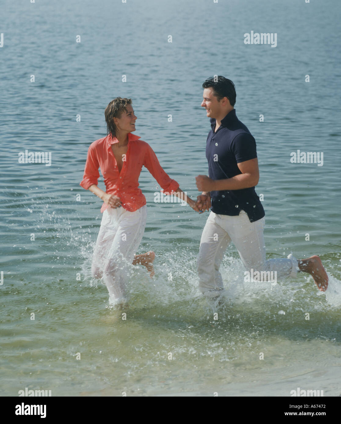 Couple running in shallow surf at beach Stock Photo Alamy