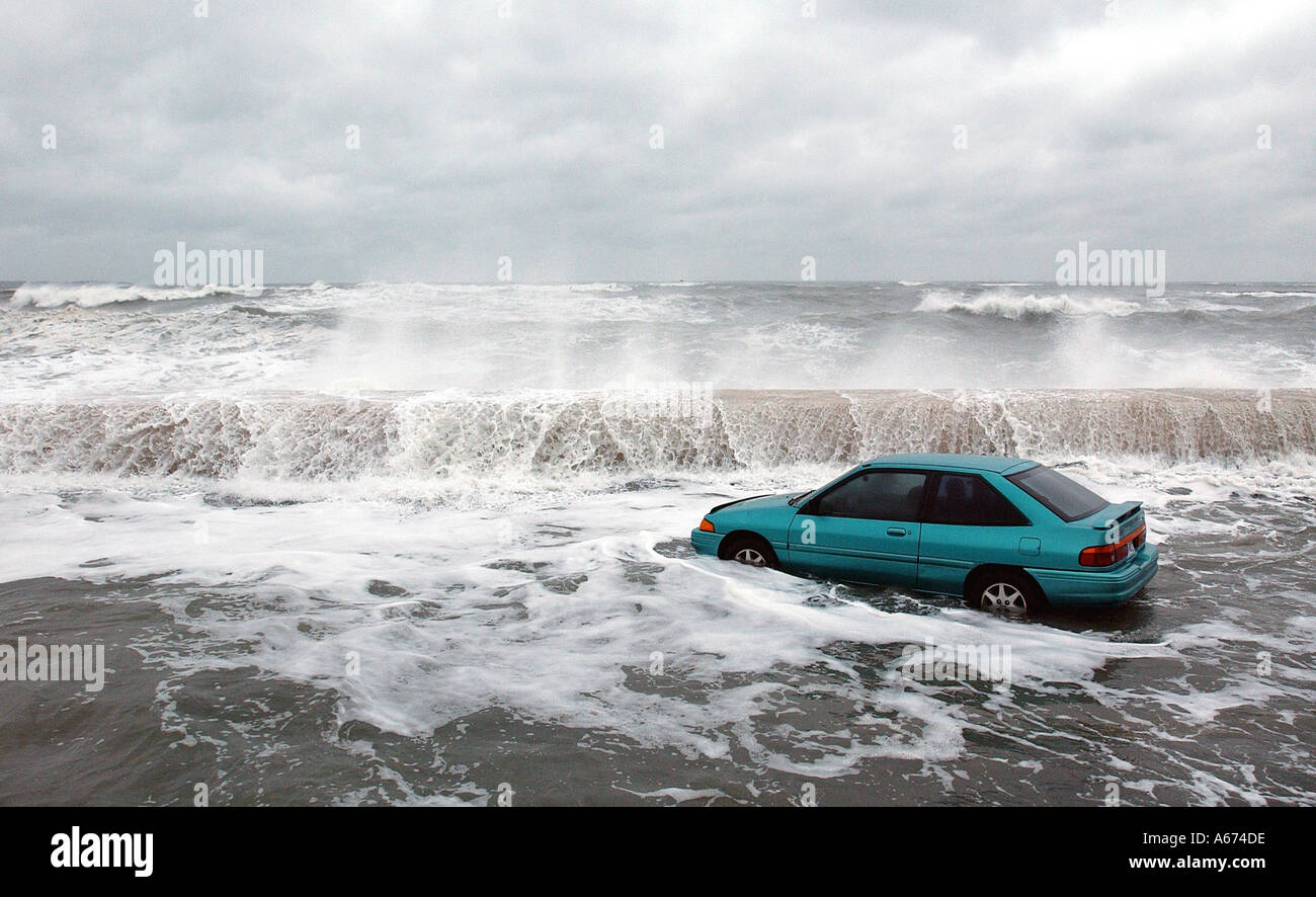 An abandoned car is stalled in flood waters as waves crash against the sea wall in Winthrop Massachusetts Stock Photo